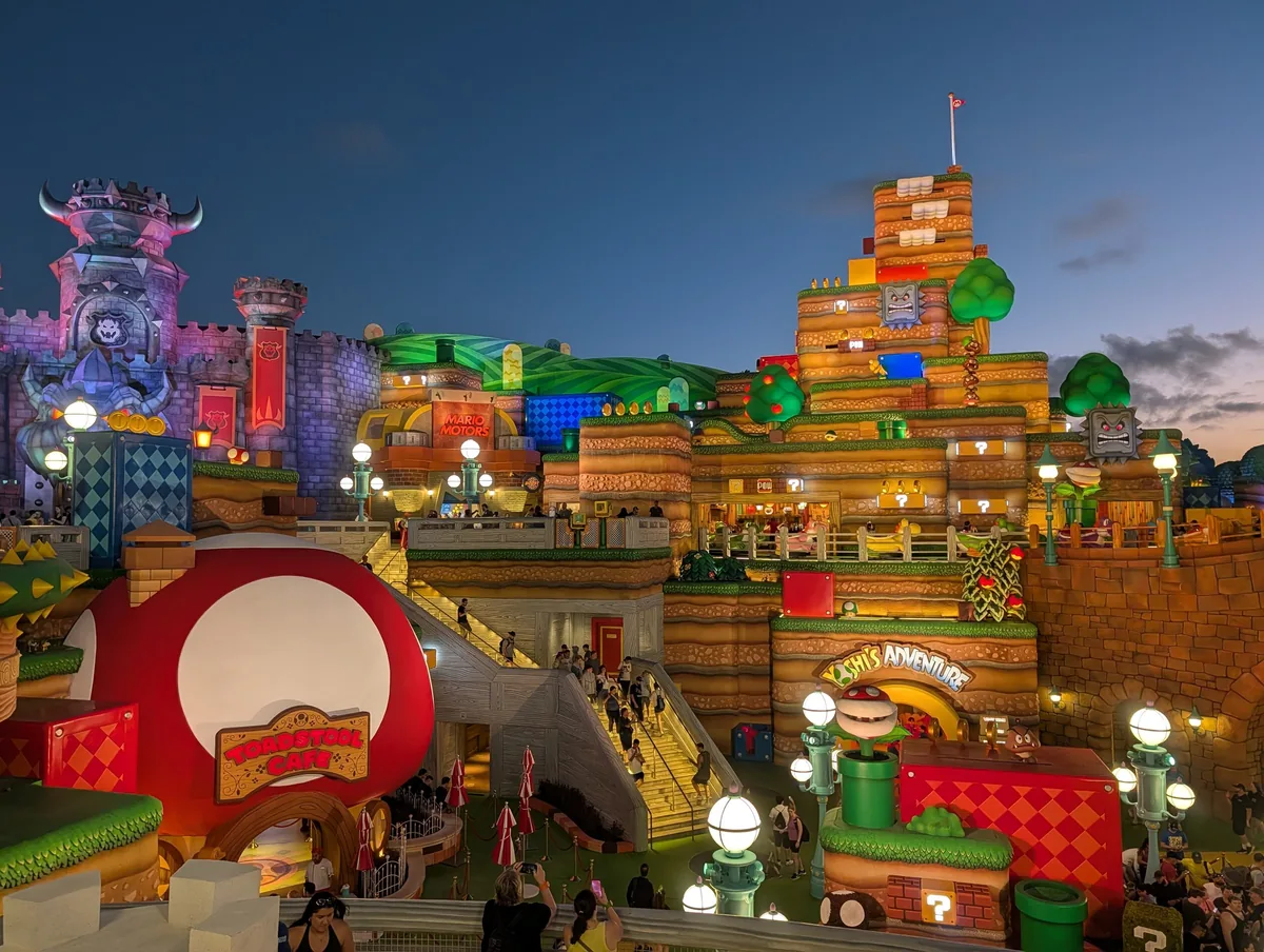 SUPER NINTENDO WORLD at Epic Universe at dusk, with Bowser's castle and lit Mushroom Kingdom terraces