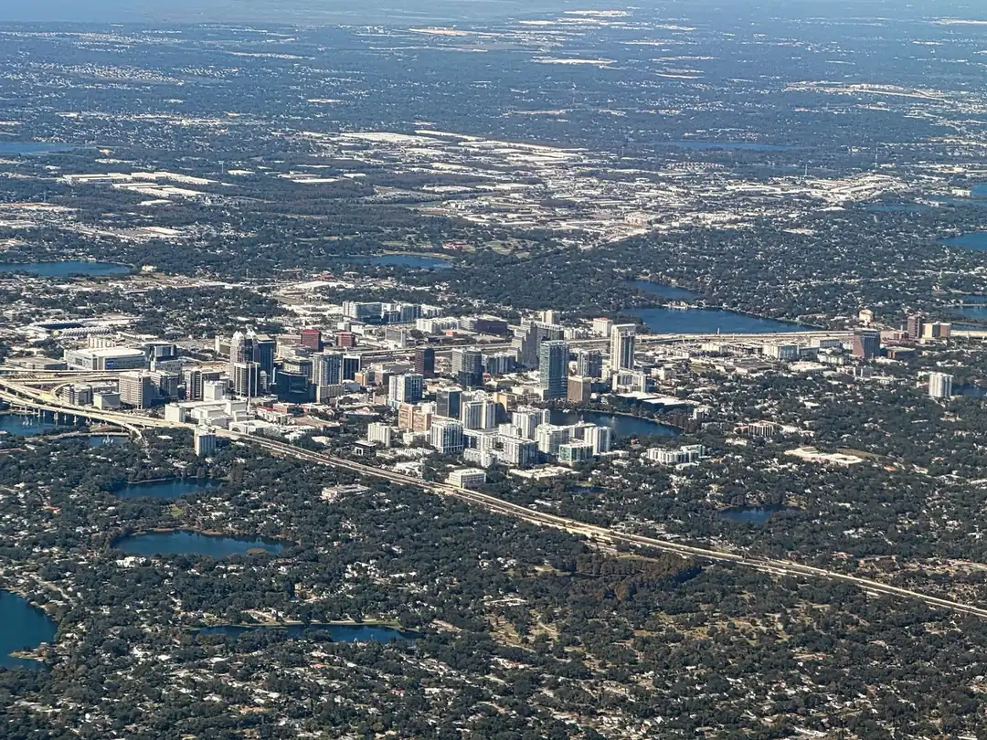 Aerial view of downtown Orlando's high-rises amid a flat spread of trees, lakes and neighborhoods