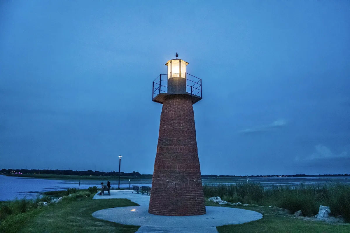 The brick Kissimmee Lighthouse glowing at dusk beside Lake Tohopekaliga in Lakefront Park