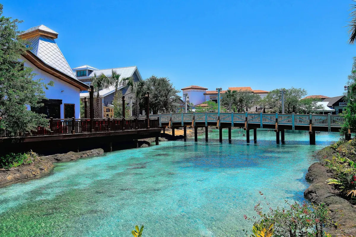 Turquoise spring and wooden footbridge beside Florida-style shops at Disney Springs Town Center