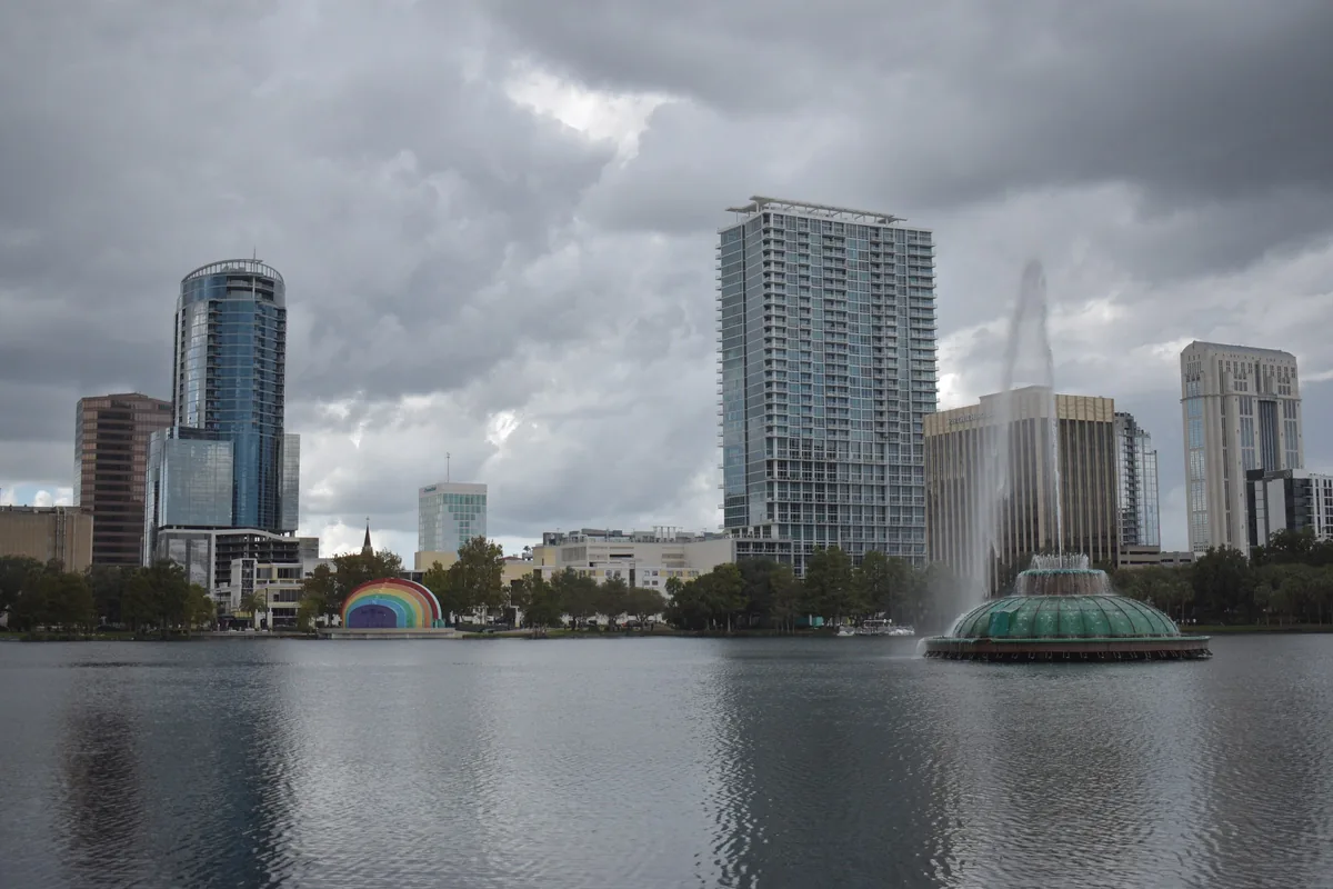 Lake Eola fountain and amphitheater with downtown Orlando towers behind, under grey clouds