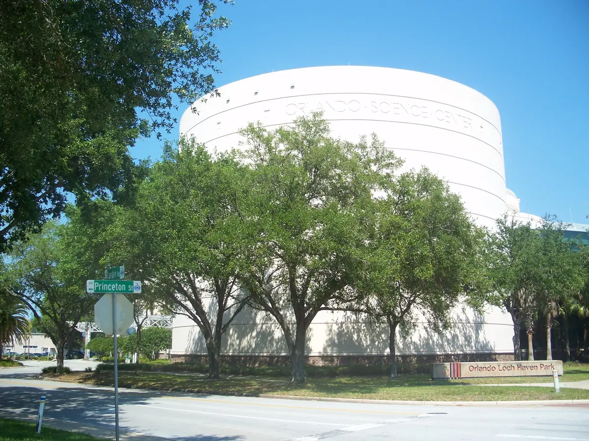 The white, drum-shaped Orlando Science Center behind live oak trees in Loch Haven Park