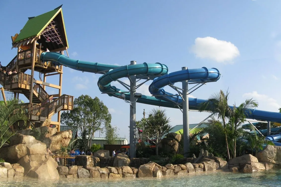 Teal and blue tube slides curving down from a wooden tower at Aquatica Orlando