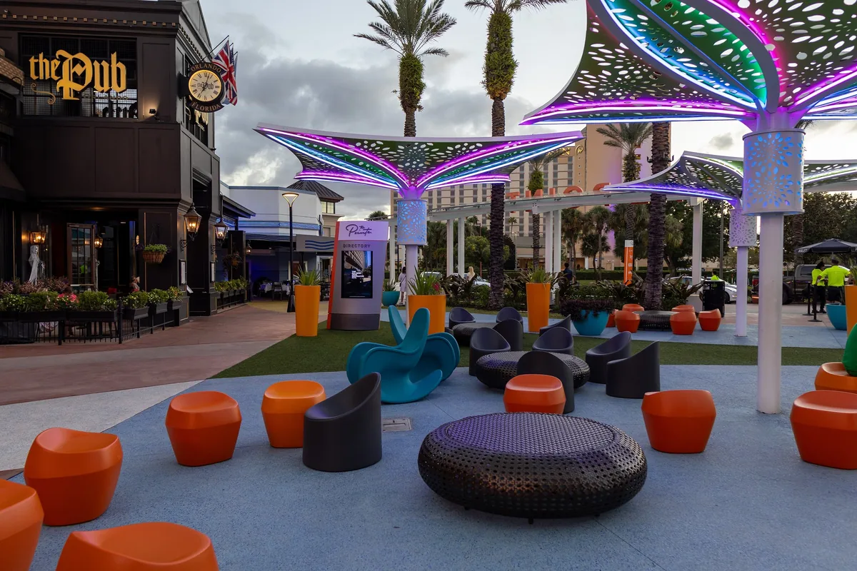 Lounge chairs under colorful lit canopies in the open-air plaza of Pointe Orlando on International Drive