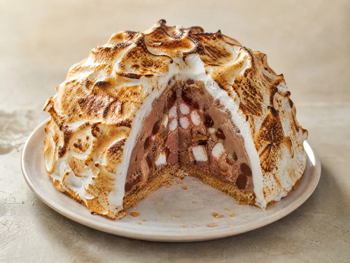 A s'mores baked Alaska cut open to show rocky road ice cream under toasted meringue