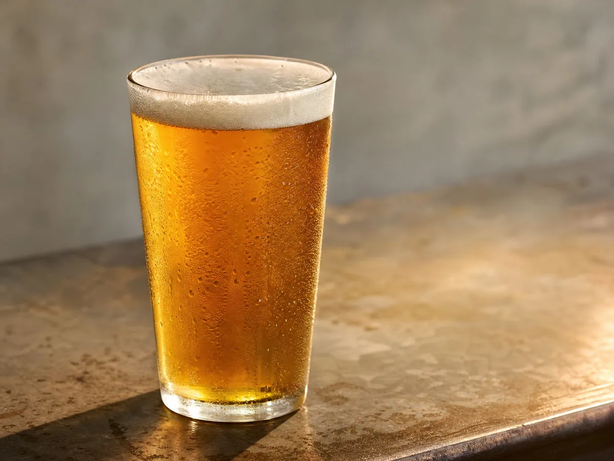 A pint of amber lager on a worn bar top