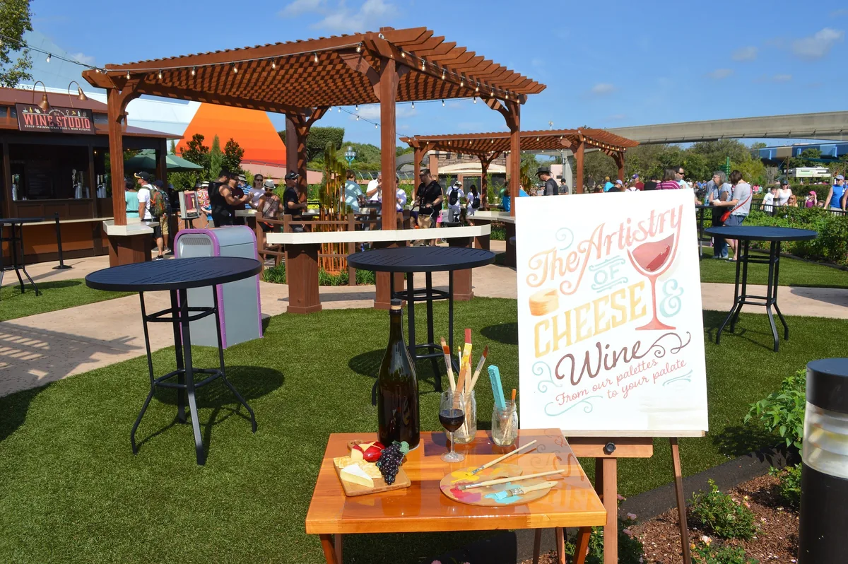 Festival tasting booth with pergola, high-top tables and a cheese and wine display at EPCOT