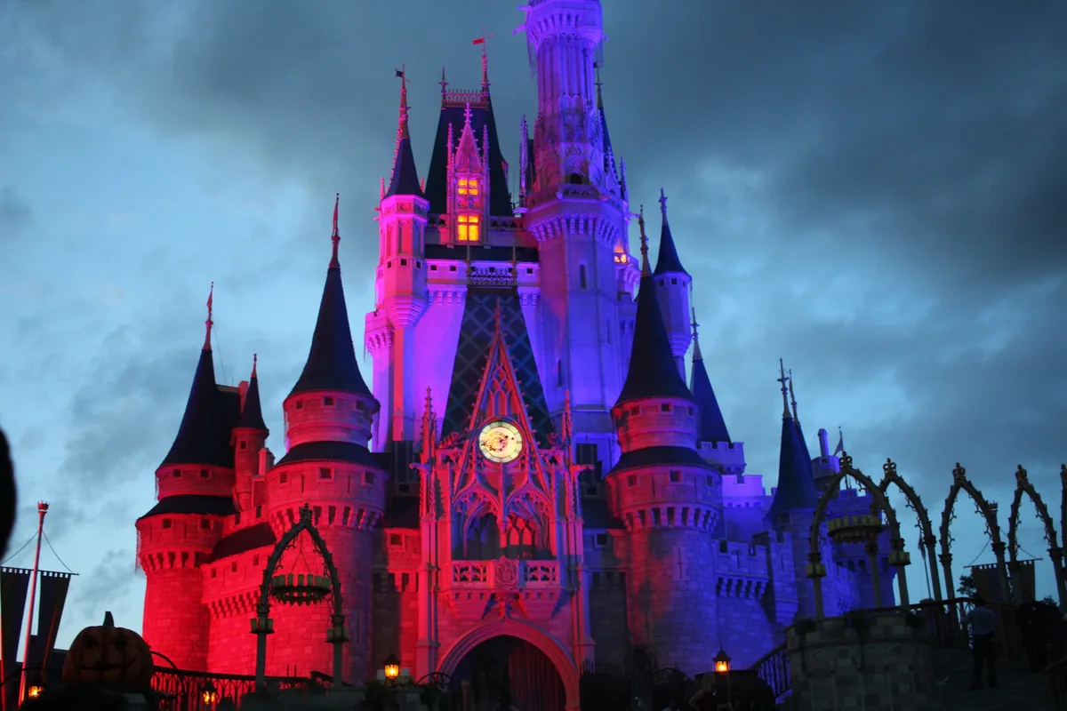 Cinderella Castle glowing red and purple at dusk during Mickey's Not-So-Scary Halloween Party