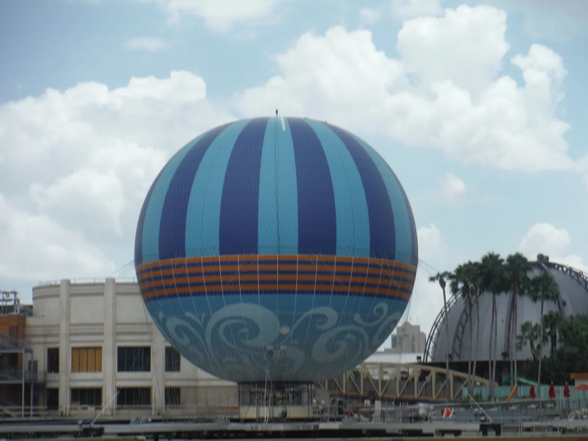 The blue-striped Aerophile tethered balloon at Disney Springs against white clouds