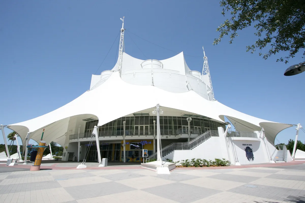 The white tent-roofed Cirque du Soleil theater at Disney Springs under a blue sky