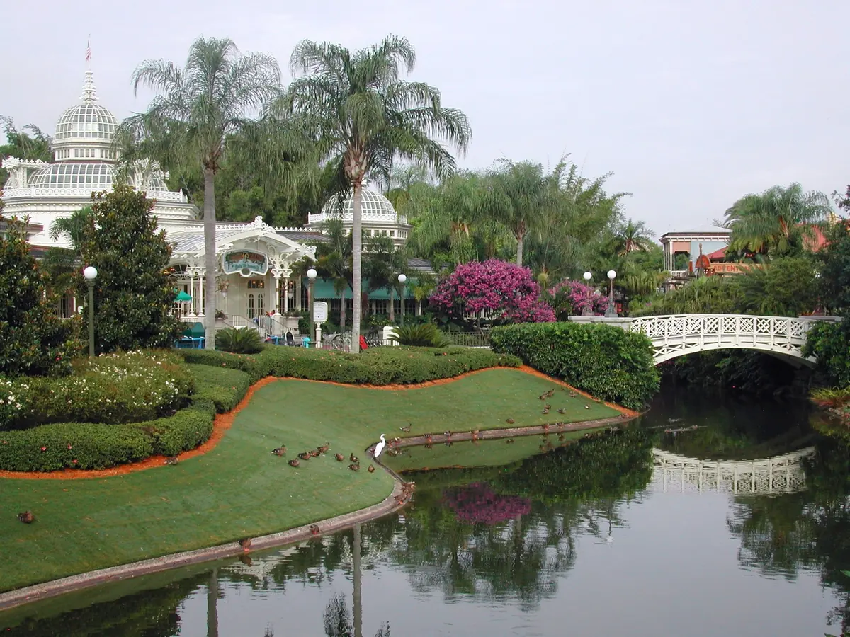 The Crystal Palace restaurant's white glass domes beside a canal and footbridge at Magic Kingdom