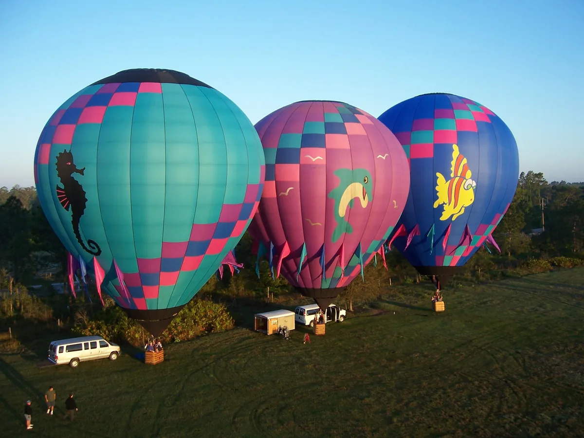 Three colorful hot-air balloons inflated on a launch field near Orlando at sunrise