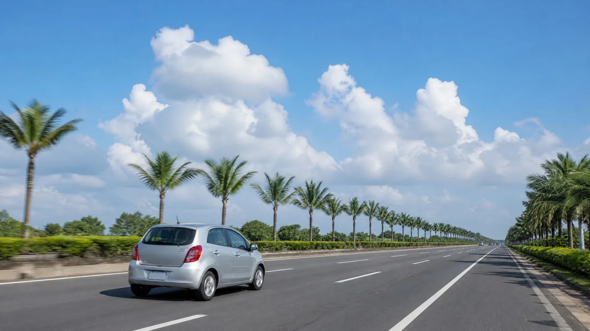 A silver compact car on a wide palm-lined highway under a blue sky