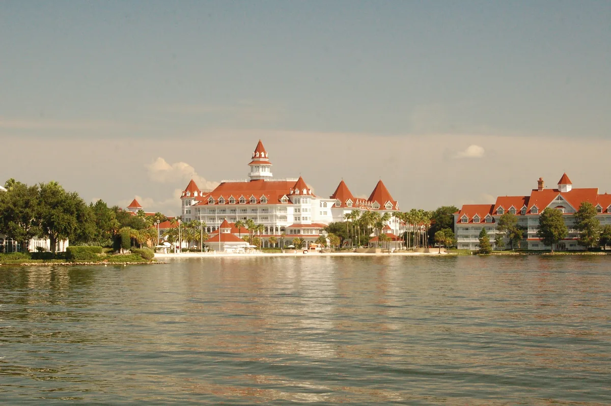 Disney's Grand Floridian Resort, white with red roofs, across the Seven Seas Lagoon at golden hour