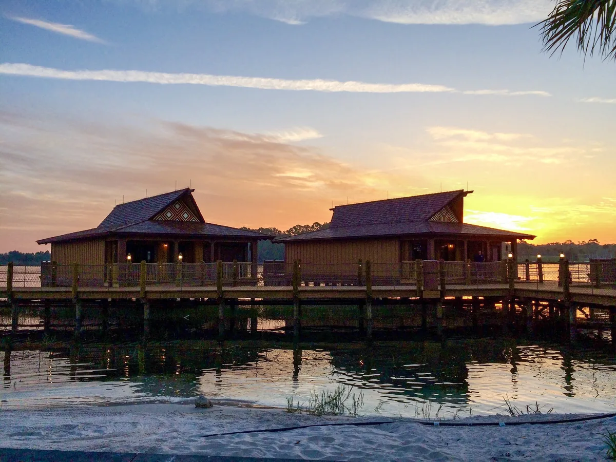 Overwater bungalows at Disney's Polynesian Village Resort against a sunset sky over the lagoon