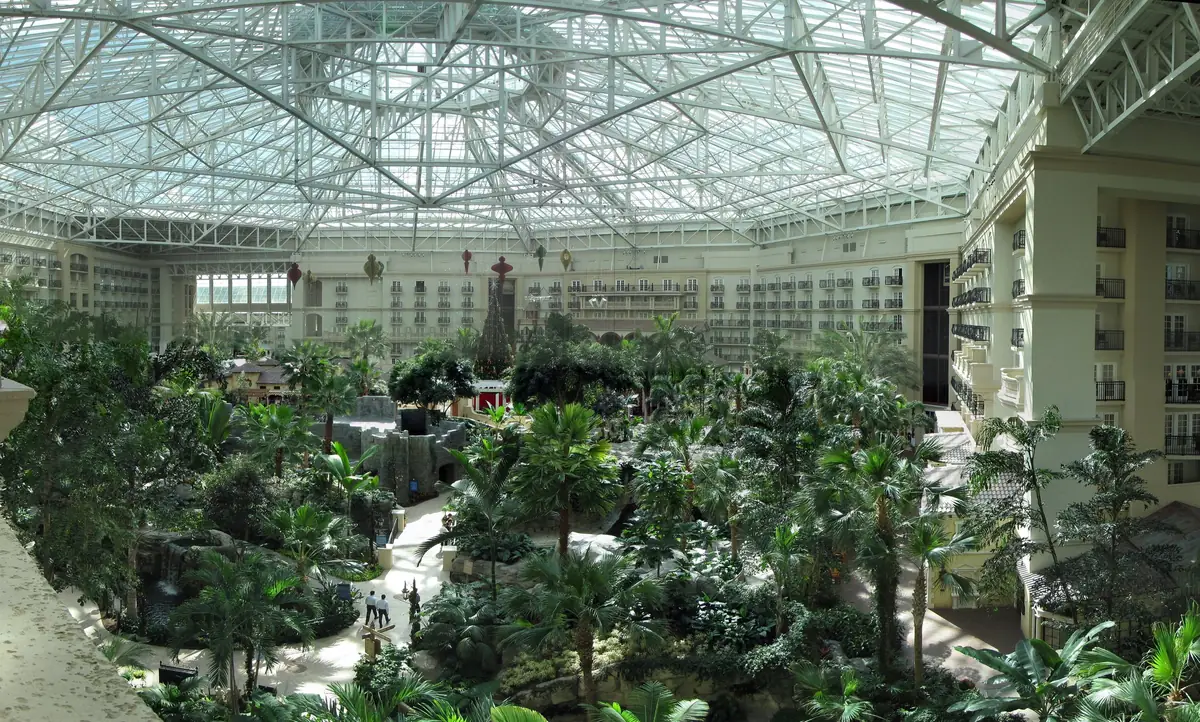 Glass-roofed atrium of Gaylord Palms Resort filled with tropical gardens below tiers of balconies