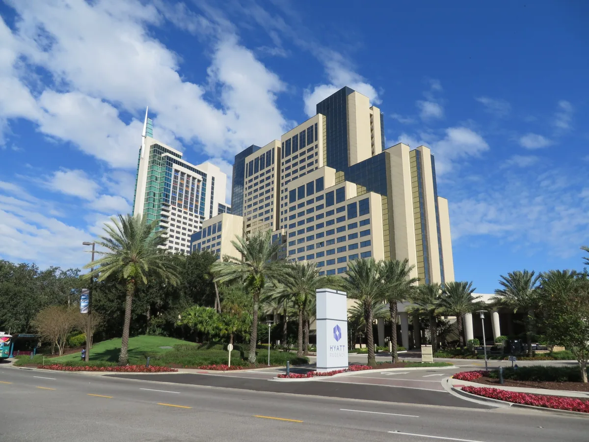 The Hyatt Regency Orlando towers behind palm trees and lawns on International Drive