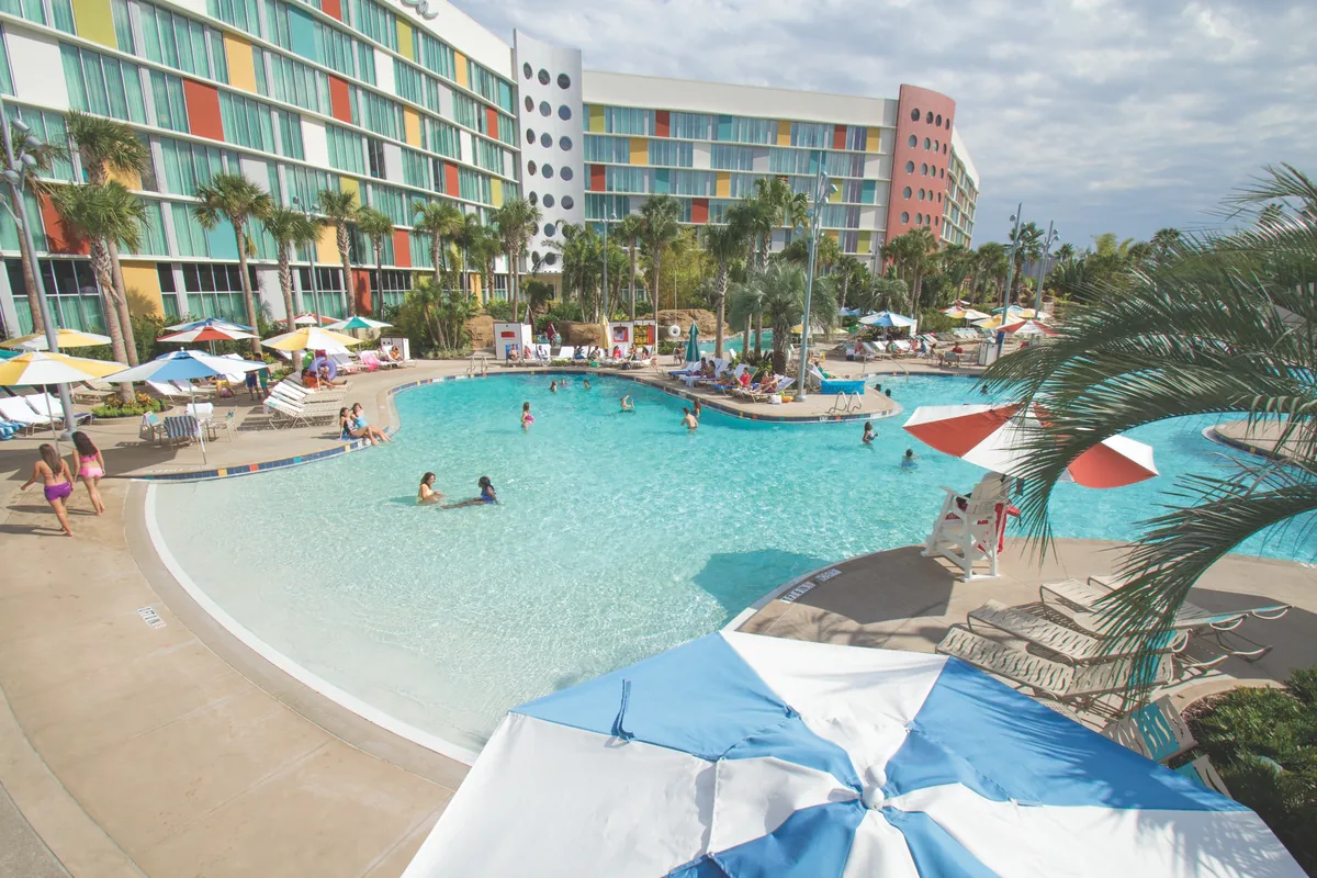 Main pool at Universal's Cabana Bay Beach Resort with umbrellas, palms and retro-colored hotel wings