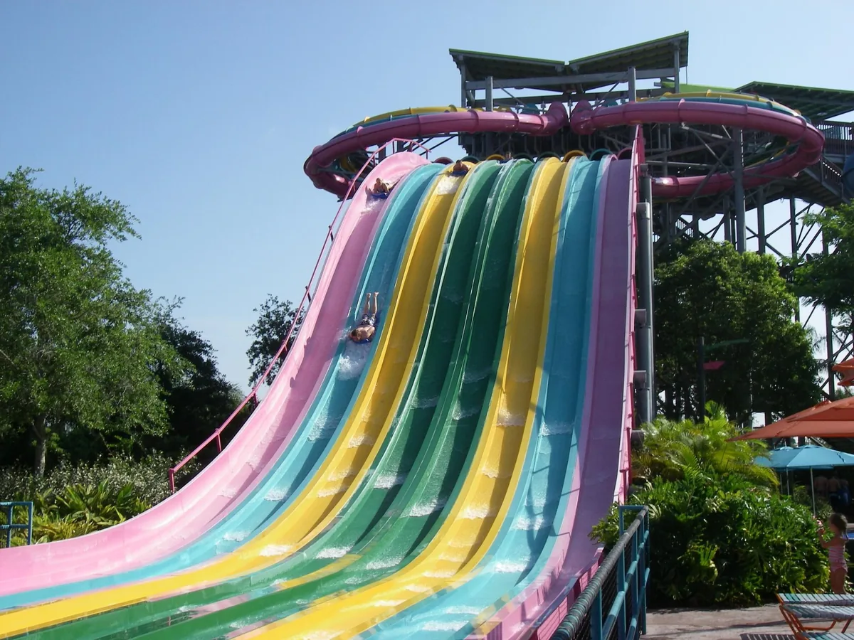 Riders on mats racing down the rainbow lanes of the Taumata Racer slide at Aquatica Orlando