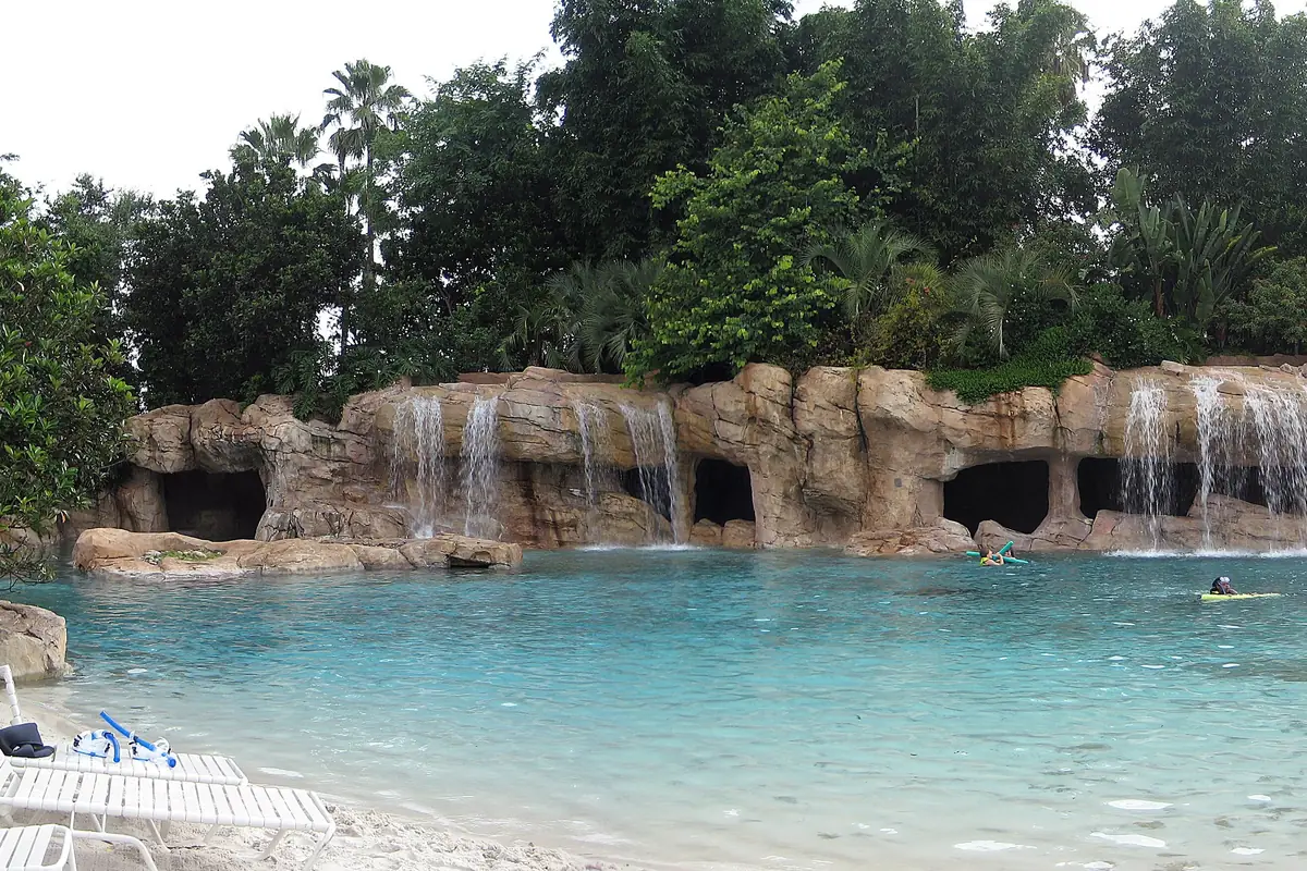 Discovery Cove's sandy beach and lagoon with lounge chairs and a rocky waterfall grotto