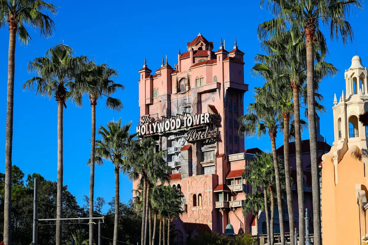 The Hollywood Tower Hotel, home of Tower of Terror, rising behind tall palm trees at Hollywood Studios