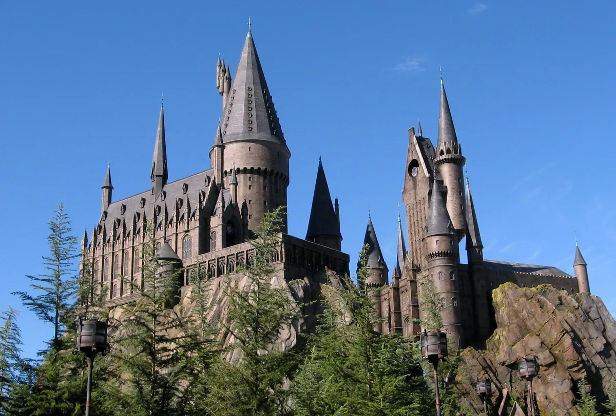 Hogwarts Castle on a rocky crag above pine trees against a blue sky at Islands of Adventure