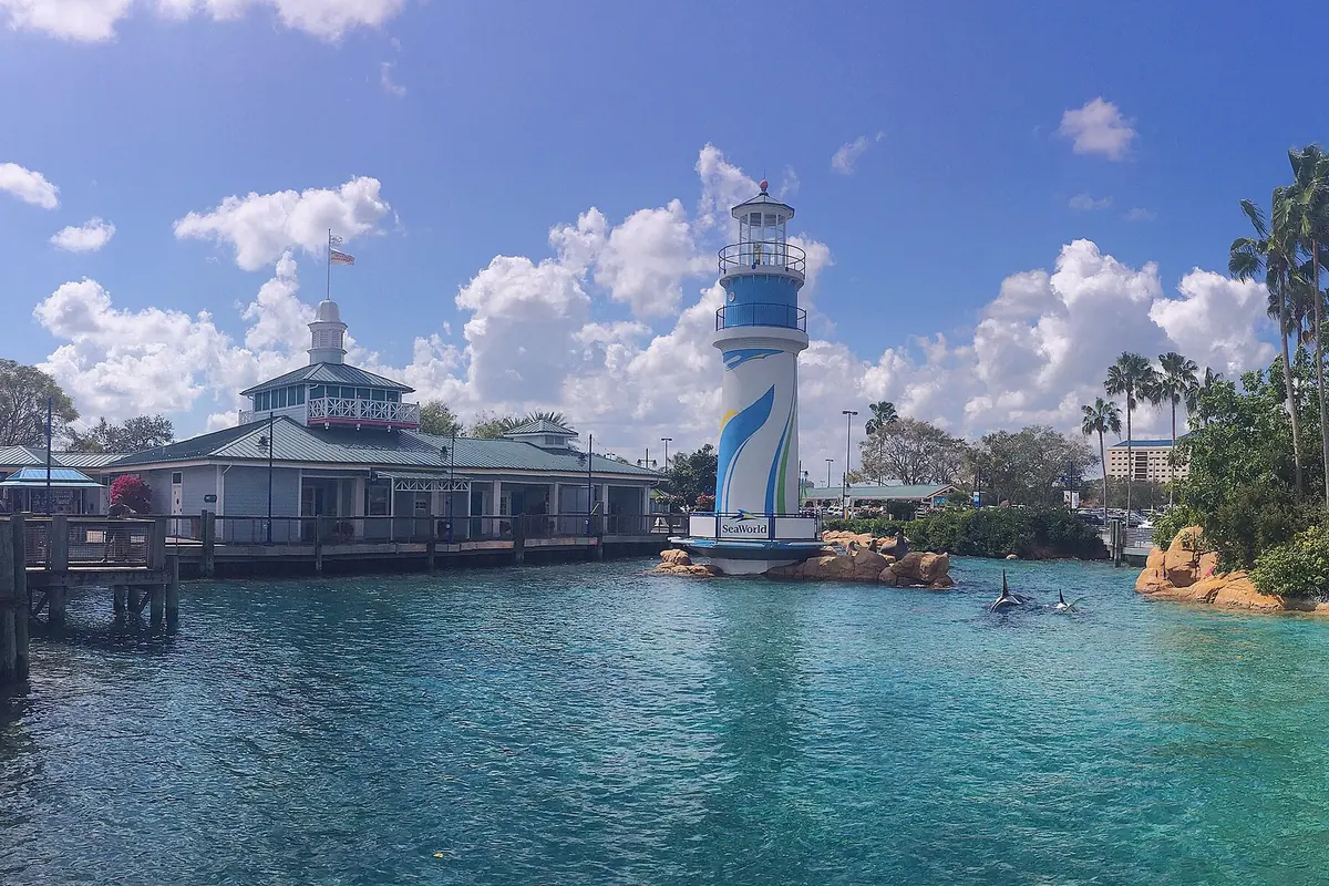 SeaWorld Orlando's entrance lighthouse beside a turquoise lagoon lined with palm trees