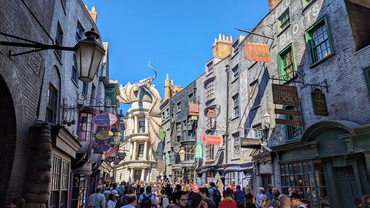 Crowded Diagon Alley at Universal Studios Florida with the Gringotts dragon perched above the shops