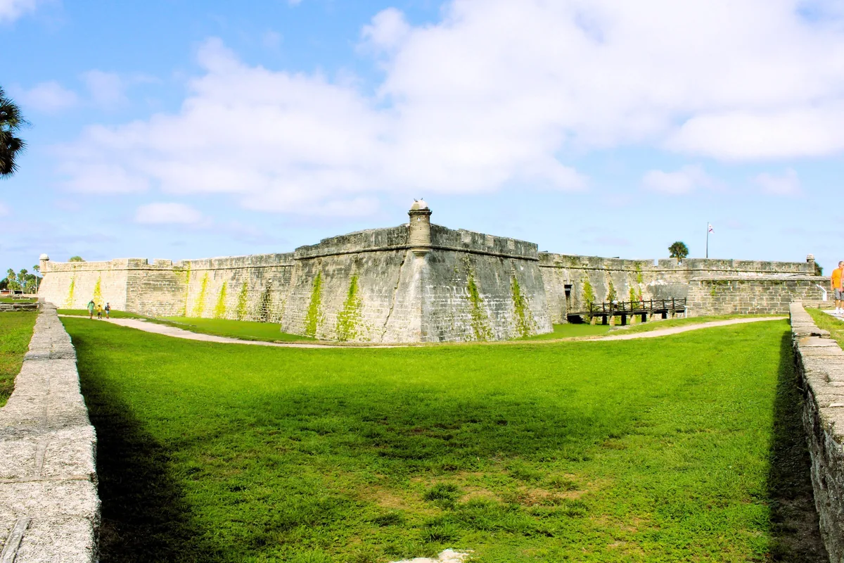 Coquina walls and watchtower of the Castillo de San Marcos across its grassy moat in St. Augustine